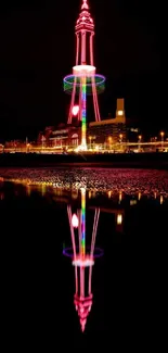 Vibrant light tower reflecting on water at night.