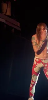 Performer on stage in red floral pants during live concert.