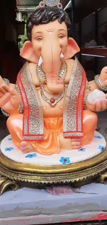 Vibrant Lord Ganesha statue in colorful attire on a decorative pedestal.