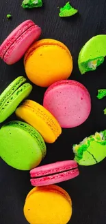 Bright macarons scattered on black background.