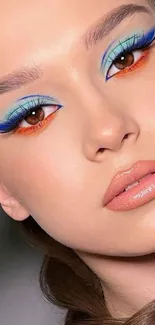 Close-up of bold eye makeup with blue and orange accents on peach-toned skin.