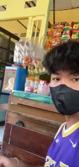 Man in mask at colorful market stall with snacks.