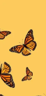 Yellow background with flying orange monarch butterflies.