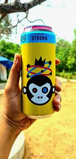 A vibrant energy drink can with a monkey graphic held outdoors.