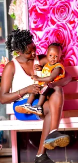 Mother and child sitting on a bench with floral background.