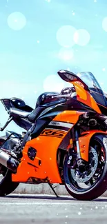 Orange superbike under a blue sky with bokeh.