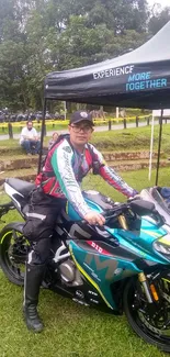 Motorcyclist posing with vibrant bike in park setting.