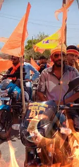 Motorcycle procession with orange flags waving in lively scene.