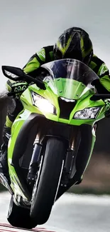 Vibrant green motorcycle racing down a track at high speed.