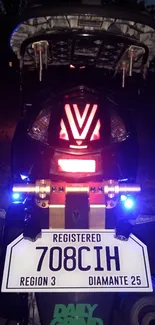 Motorcycle rear view with glowing lights at night.