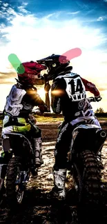 Two motocross riders under a vibrant sunset sky.
