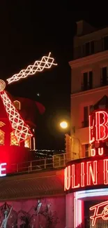 Night view of Moulin Rouge in Paris with vibrant red neon lights.