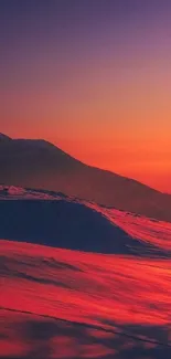 Fiery orange sunset over snow-covered mountains.