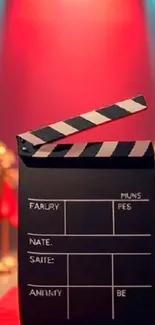Clapperboard on red carpet backdrop with vibrant lights.
