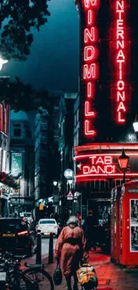 Nighttime city street with neon signs glowing.