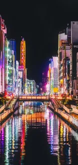 Colorful neon-lit cityscape reflecting on river at night.