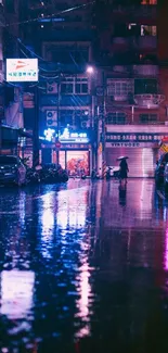 Neon-lit city street at night with reflections on wet pavement.