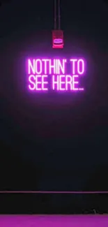 Neon pink 'Nothin' To See Here' sign on dark background.