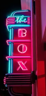 Vibrant neon sign reading 'The Box' against a night sky in an urban setting.