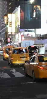 Bustling New York City street with yellow taxis under city lights at night.