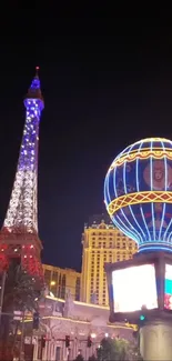 Vibrant night view of illuminated Eiffel-style tower and neon globe in cityscape.