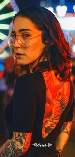 Woman at a vibrant festival with tattoos and bright lights.