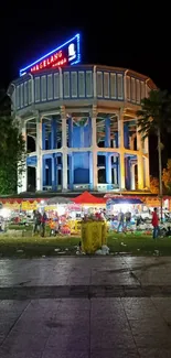 Night market scene in Magelang with bright lights and palm trees.