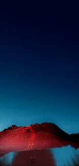 Red mountain under a dark blue starry night sky.