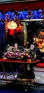 Vibrant temple at night with colorful lights and offerings against a dark backdrop.