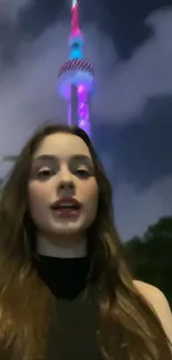 Young woman in front of a lit-up tower at night.