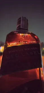 Red whiskey bottle glowing in nighttime urban setting.