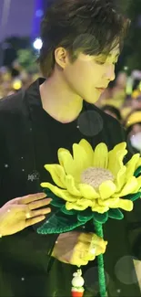 Person holding a sunflower during a vibrant night event.