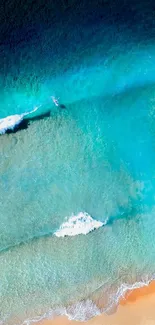 Aerial view of turquoise ocean and sandy beach with gentle waves.