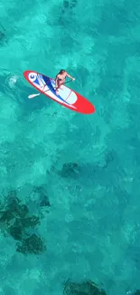 Aerial view of a lone paddleboarder on turquoise ocean waters.