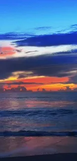 Vibrant ocean sunset with colorful sky and calm waters on a beach.