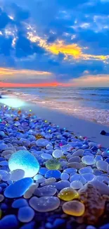 Vibrant sunset over an ocean with colorful pebbles on a serene beach.