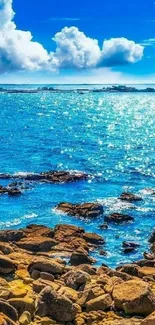 Vibrant ocean view with blue sky and rocky shore.