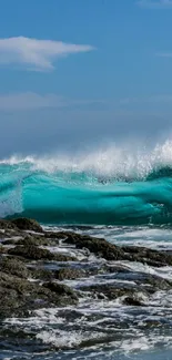 Dynamic teal ocean wave crashing on rocky shore with clear blue sky.