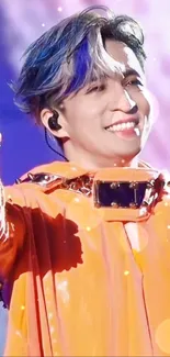 Energetic performer in orange outfit on vibrant concert stage.