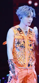 Artist in vibrant orange outfit performing on stage.