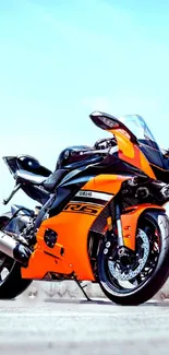 Orange motorcycle in dynamic pose on a clear sky background.