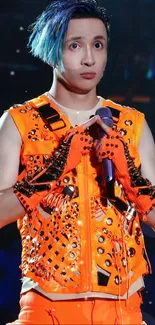 Performer in orange attire with blue highlights on stage.