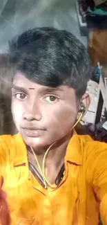 Portrait of a young man in a vibrant orange setting with a yellow shirt.