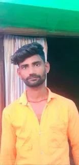 Man in vibrant orange shirt standing against a colorful background.