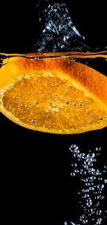 Vibrant orange slice splashing in water against a dark background.