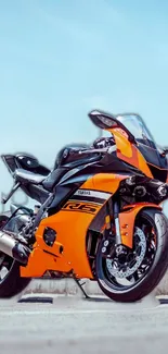 Vibrant orange sport bike against clear sky background.