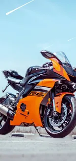 Orange sportbike standing against a clear sky background.