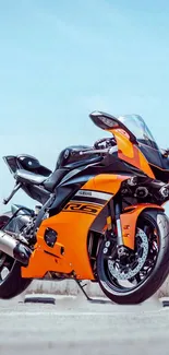 Vibrant orange sportbike parked under blue sky.