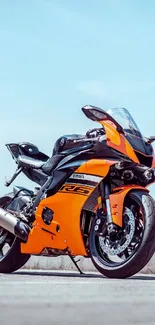 Orange sports bike beneath clear sky.