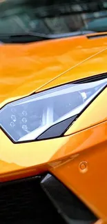 Close-up of vibrant orange sports car headlight.